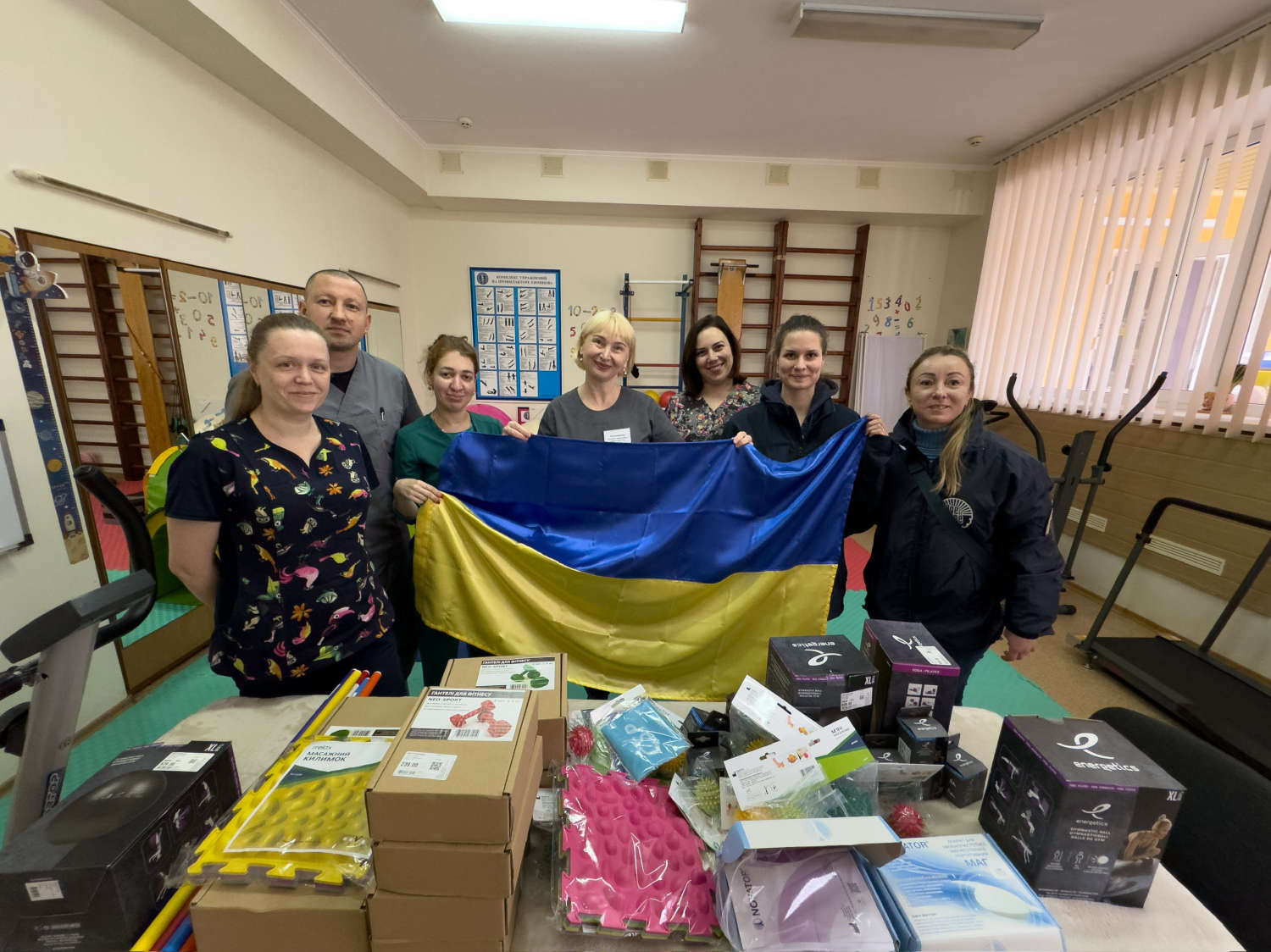 Hospital workers with a Ukrainian flag among the donated medical equipment
